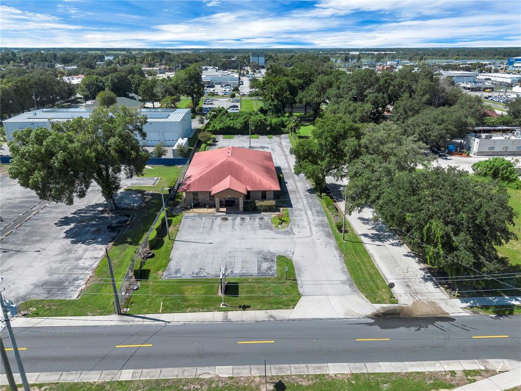 An aerial view shows a commercial building with a red roof and surrounding parking lots — 220 AVENUE O SE, WINTER HAVEN, FL