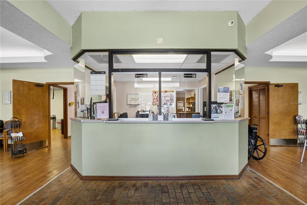 A reception desk with a glass partition sits in a room with wood flooring — 220 AVENUE O SE, WINTER HAVEN, FL