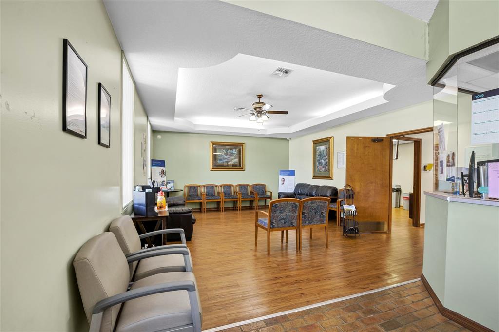 A waiting room features wood-look flooring, a tray ceiling with a fan, and multiple chairs — 220 AVENUE O SE, WINTER HAVEN, FL