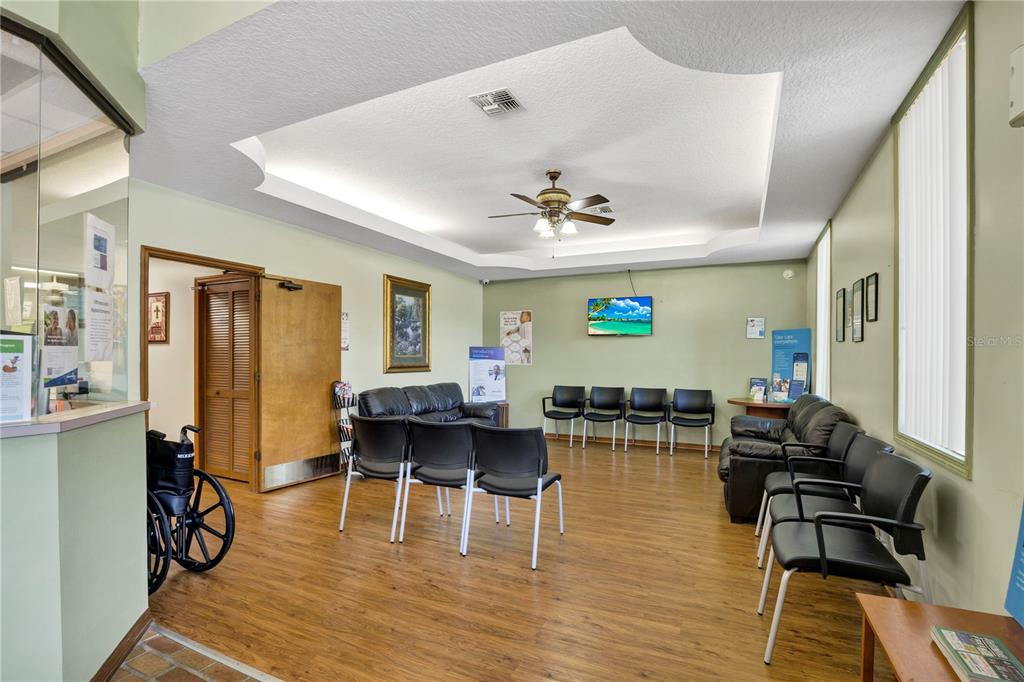 A waiting room features wood-look flooring, black chairs, leather sofas, and a tray ceiling — 220 AVENUE O SE, WINTER HAVEN, FL
