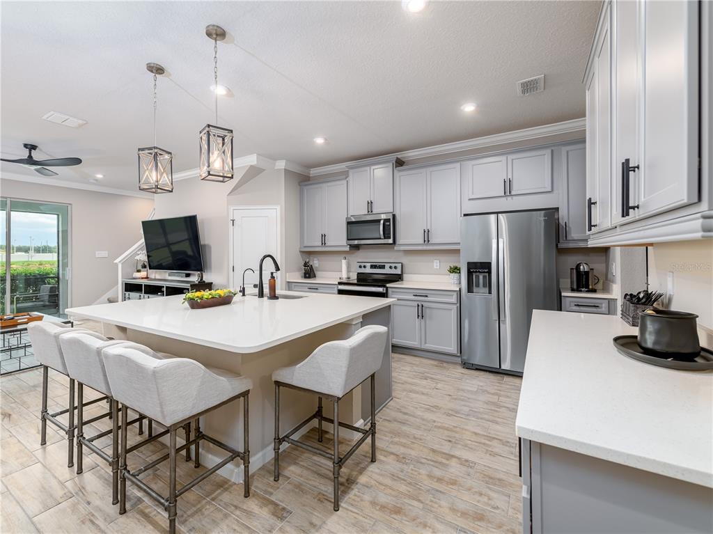 A view from a hallway into an open-concept kitchen and living area with tile floors — 19319 BLUE POND DRIVE UNIT 22, LUTZ, FL
