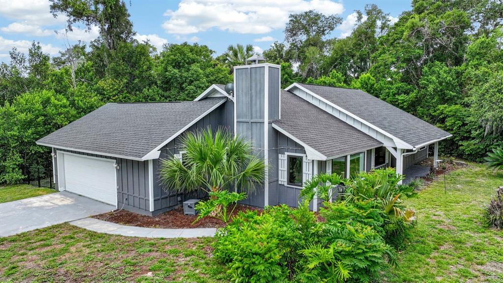 The exterior of a single-story house features gray vertical siding, white shutters, and a porch — 11 RIO PINAR TRAIL, ORMOND BEACH, FL