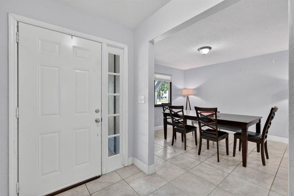 A dining room features a dark wood table, four chairs, tile flooring, and two floor lamps — 11 RIO PINAR TRAIL, ORMOND BEACH, FL