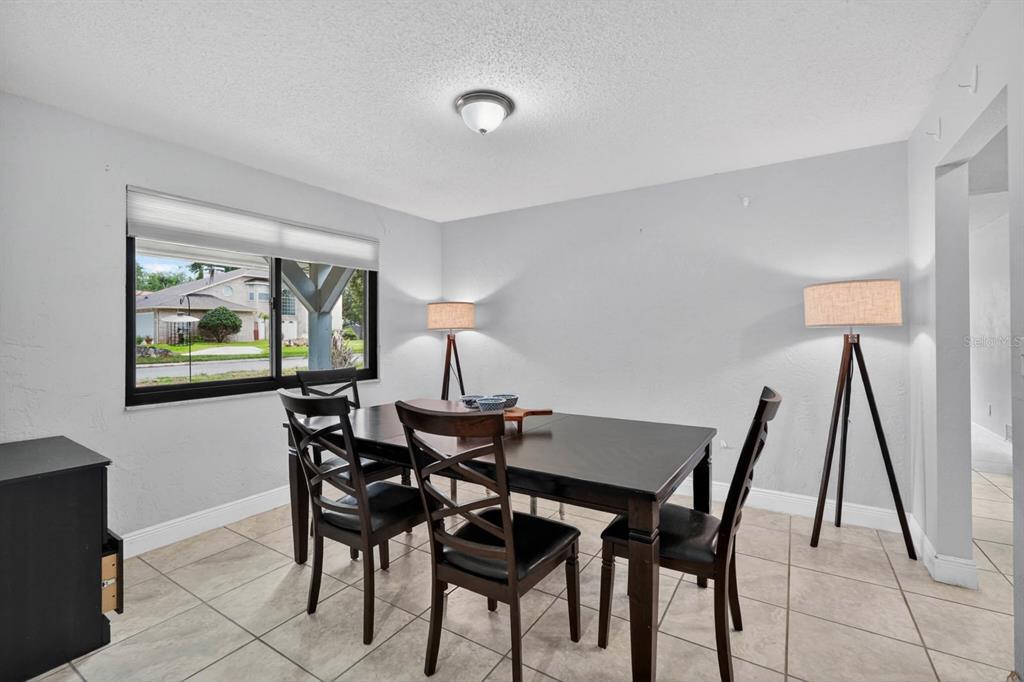A dining area with tile floors opens into a living space with a sliding glass door — 11 RIO PINAR TRAIL, ORMOND BEACH, FL