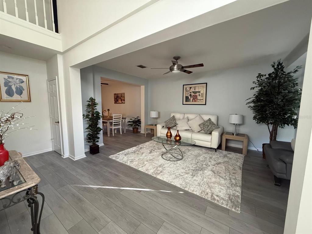 A living room with light gray wood-look flooring, a white sofa, and a glass coffee table — 424 FLATWOOD DRIVE, WINTER SPRINGS, FL
