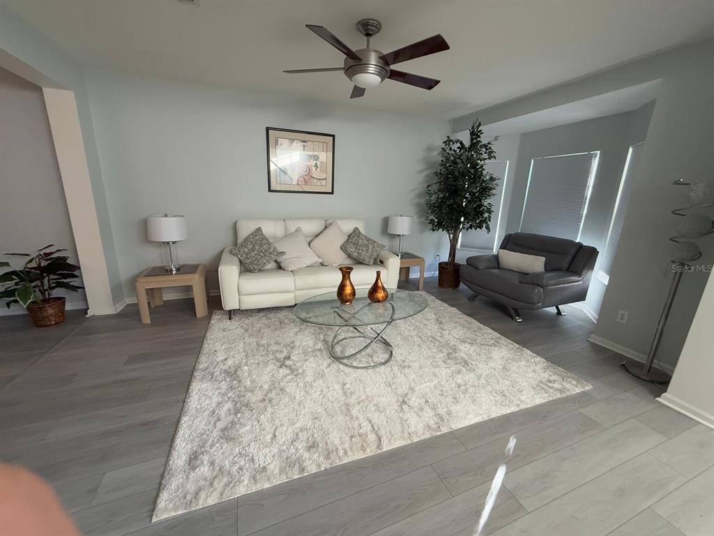 A living room features a white sofa, a grey armchair, and a glass coffee table — 424 FLATWOOD DRIVE, WINTER SPRINGS, FL