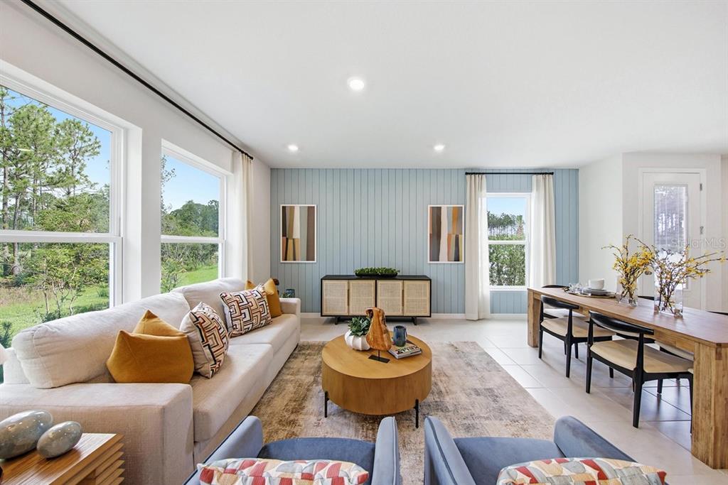 A living and dining area features a light blue paneled wall, wood furniture, and large windows — 1140 WILD CREST LANE, DAYTONA BEACH, FL