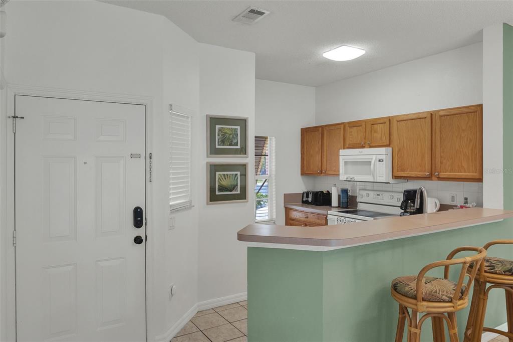 A dining area and living room with tile floors, a green accent wall, and patio access — 1086 PARK RIDGE CIRCLE, KISSIMMEE, FL