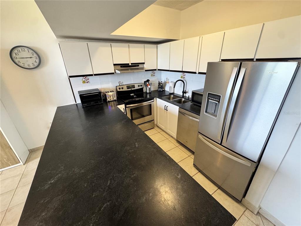 A kitchen features dark countertops, white cabinetry, and stainless steel appliances — 222 BEACH VILLAGE UNIT 222, HUMACAO, PR