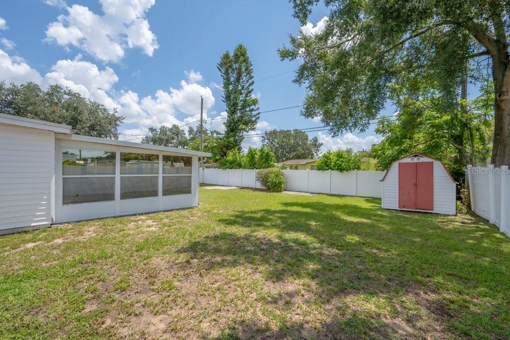 A backyard features a white enclosed patio, a small storage shed, and a white vinyl fence — 1105 N PARSONS AVENUE, BRANDON, FL