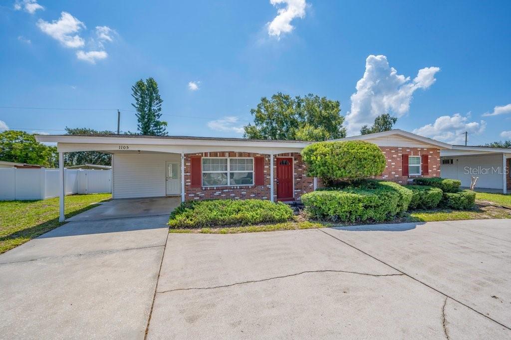 A single-story brick house with a carport, red shutters, and a large concrete driveway — 1105 N PARSONS AVENUE, BRANDON, FL