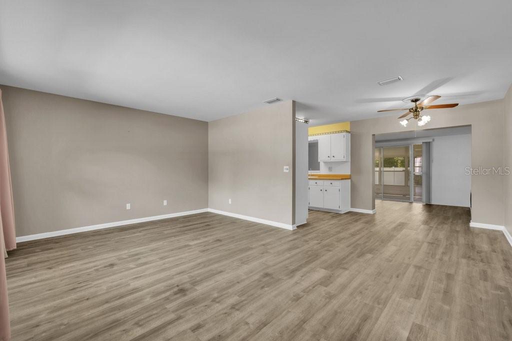 An open living area features light wood-look flooring and a view into the kitchen — 1105 N PARSONS AVENUE, BRANDON, FL