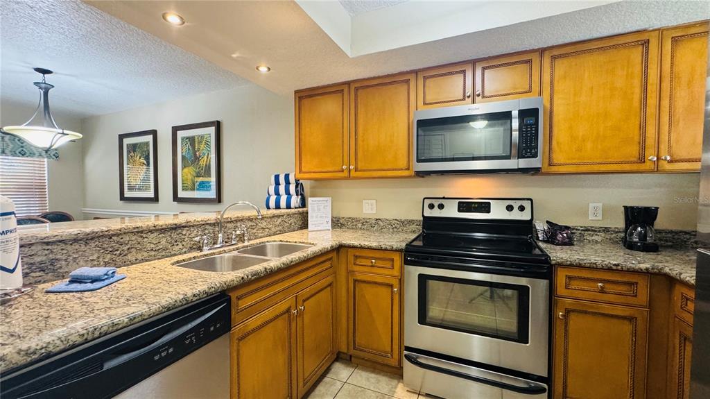 A kitchen features wood cabinets, granite countertops, and stainless steel appliances — 1125 SPACEPORT COURT, KISSIMMEE, FL