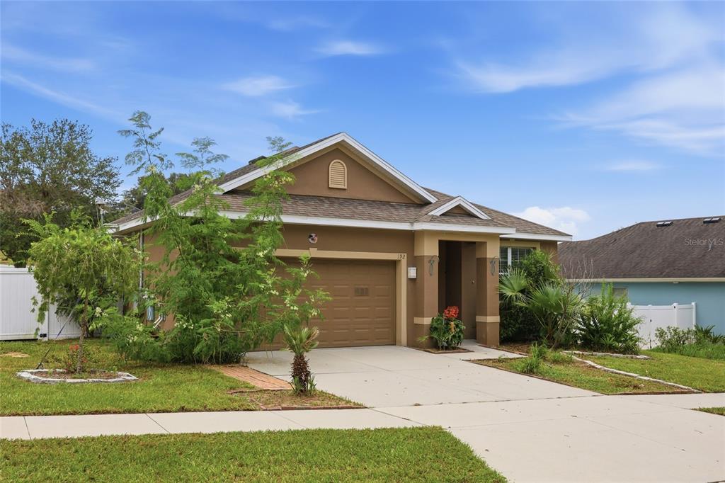 A tan stucco house exterior features a purple front door and a small welcome mat — 192 BLACKSTONE CREEK ROAD, GROVELAND, FL