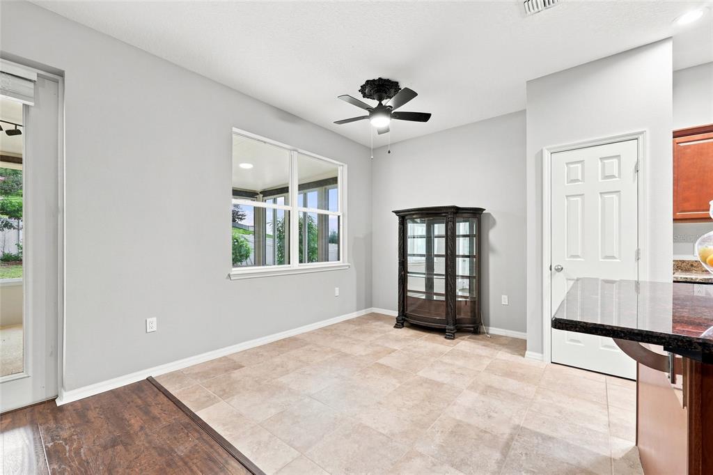 A spacious room features light gray walls, dark wood-look flooring, a ceiling fan, and a glass door — 192 BLACKSTONE CREEK ROAD, GROVELAND, FL