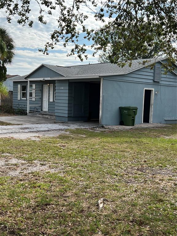 A blue single-story house features a covered carport, a front entrance, and a green trash bin — 2106 MAGNOLIA STREET, SARASOTA, FL
