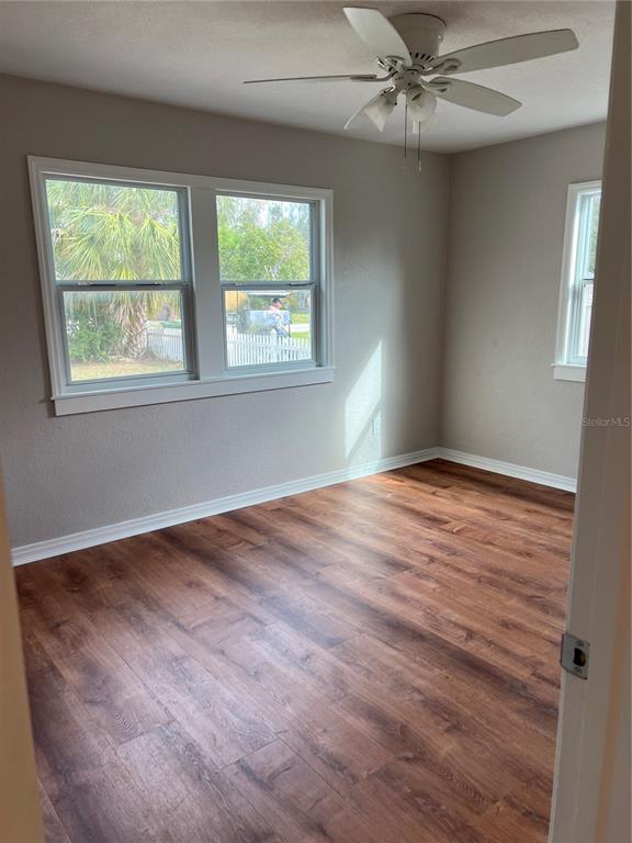 An empty bedroom features wood-look laminate flooring, light gray walls, and a white ceiling fan — 2106 MAGNOLIA STREET, SARASOTA, FL