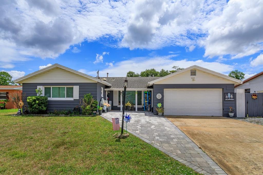 A single-story house with gray siding, a white garage door, and a paved walkway — 5325 SHARLENE DR, TITUSVILLE, FL