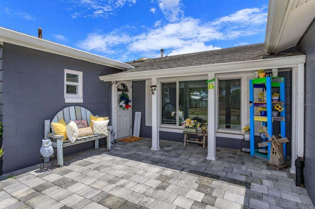 A paved patio area features a wooden bench, a colorful shelving unit, and a front door — 5325 SHARLENE DR, TITUSVILLE, FL