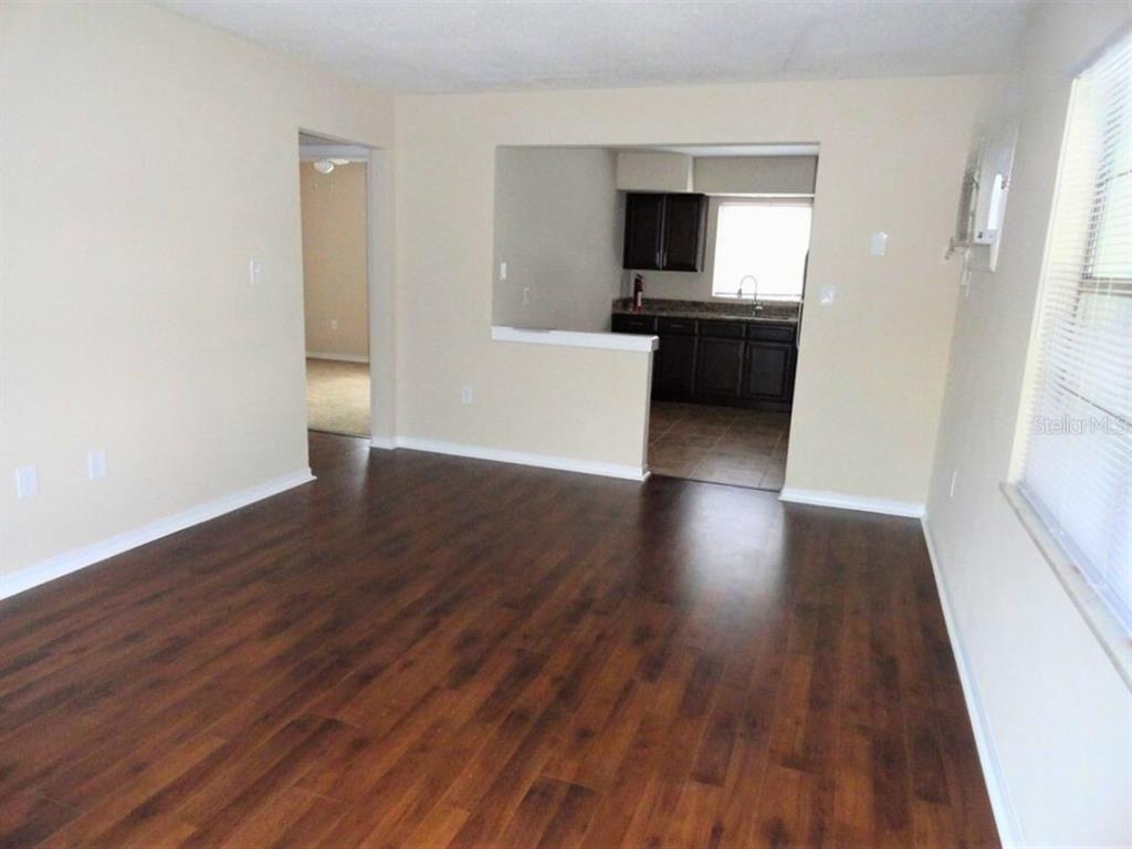 A living room with dark wood-look flooring opens to a kitchen with dark cabinets — 610 S LAKE FORMOSA DRIVE, ORLANDO, FL