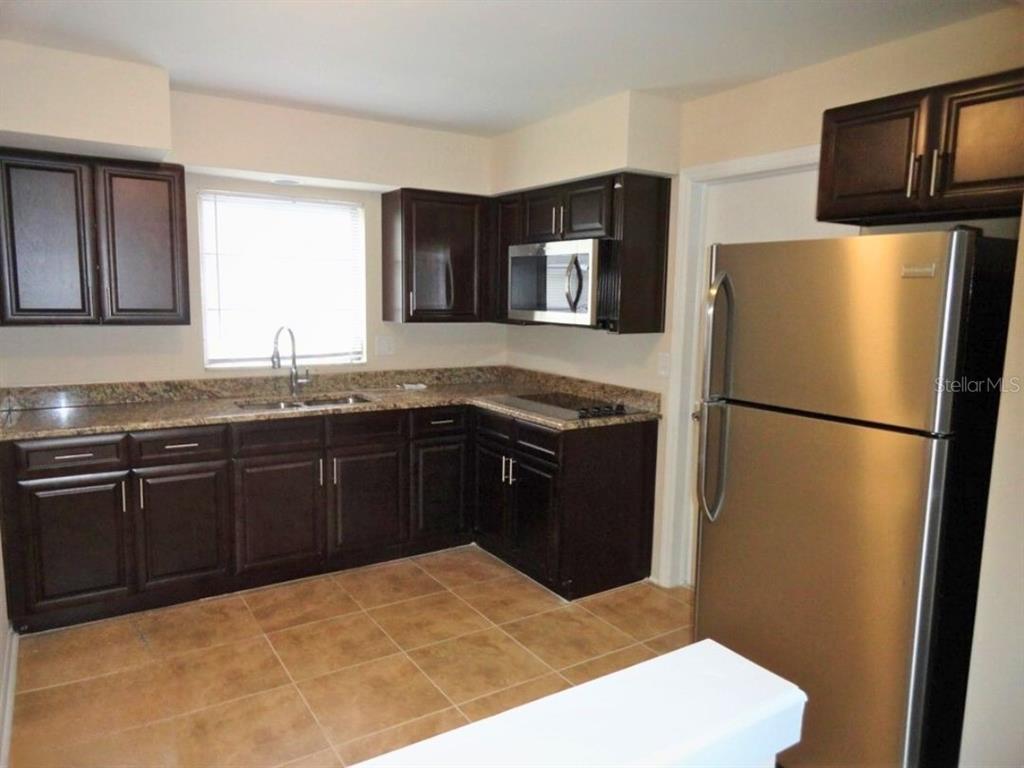 A kitchen with dark wood cabinets, granite countertops, and stainless steel appliances — 610 S LAKE FORMOSA DRIVE, ORLANDO, FL