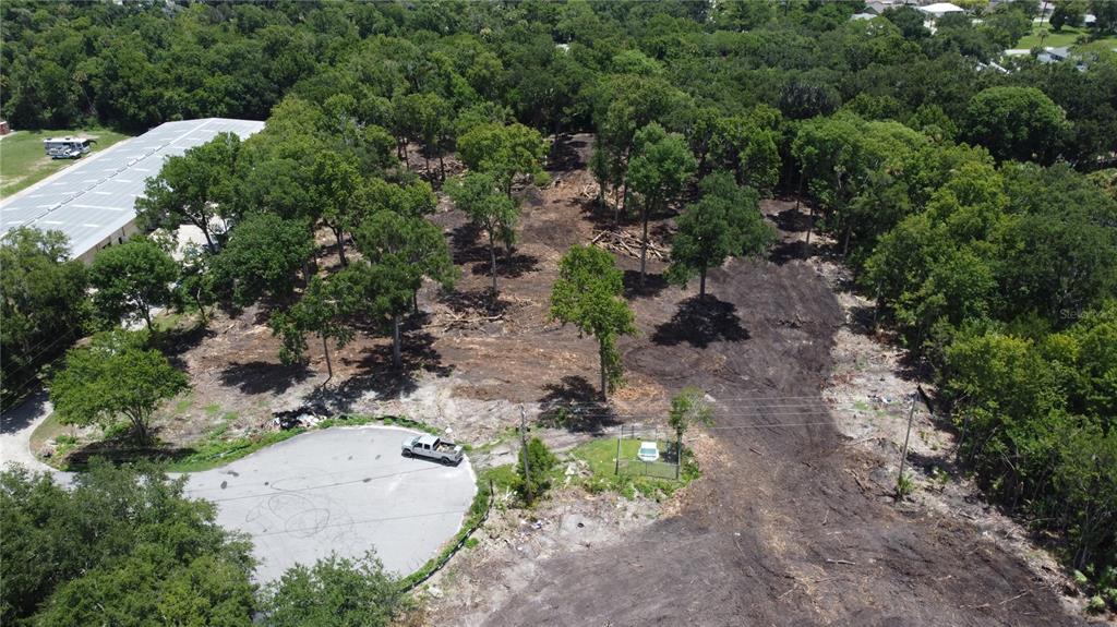 An aerial view shows a cleared, wooded lot adjacent to a cul-de-sac and industrial building — 843 GATEPARK DRIVE, DAYTONA BEACH, FL