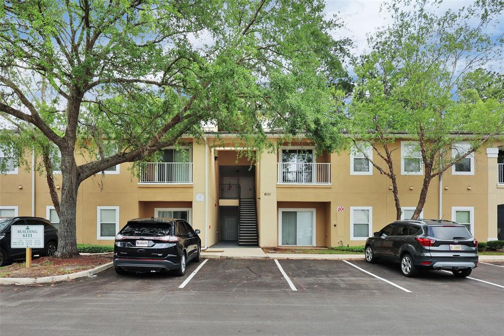A two-story apartment building with tan stucco walls, balconies, and a central staircase — 6111 MAGGIES CIRCLE UNIT 110, JACKSONVILLE, FL