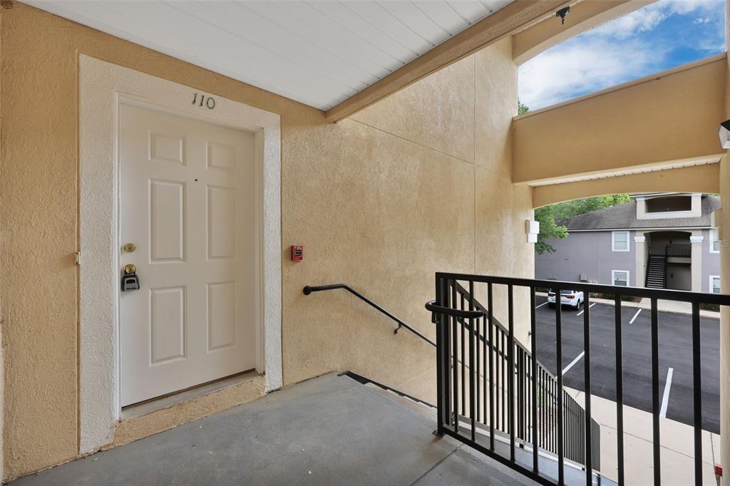 An exterior view of a residential apartment entrance with a white door and metal railing — 6111 MAGGIES CIRCLE UNIT 110, JACKSONVILLE, FL