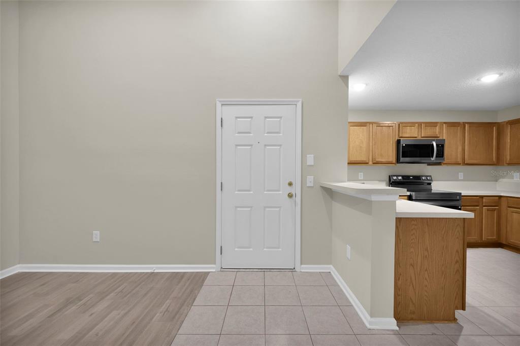 A view of an entryway with tile flooring leading into a kitchen with wood cabinets — 6111 MAGGIES CIRCLE UNIT 110, JACKSONVILLE, FL