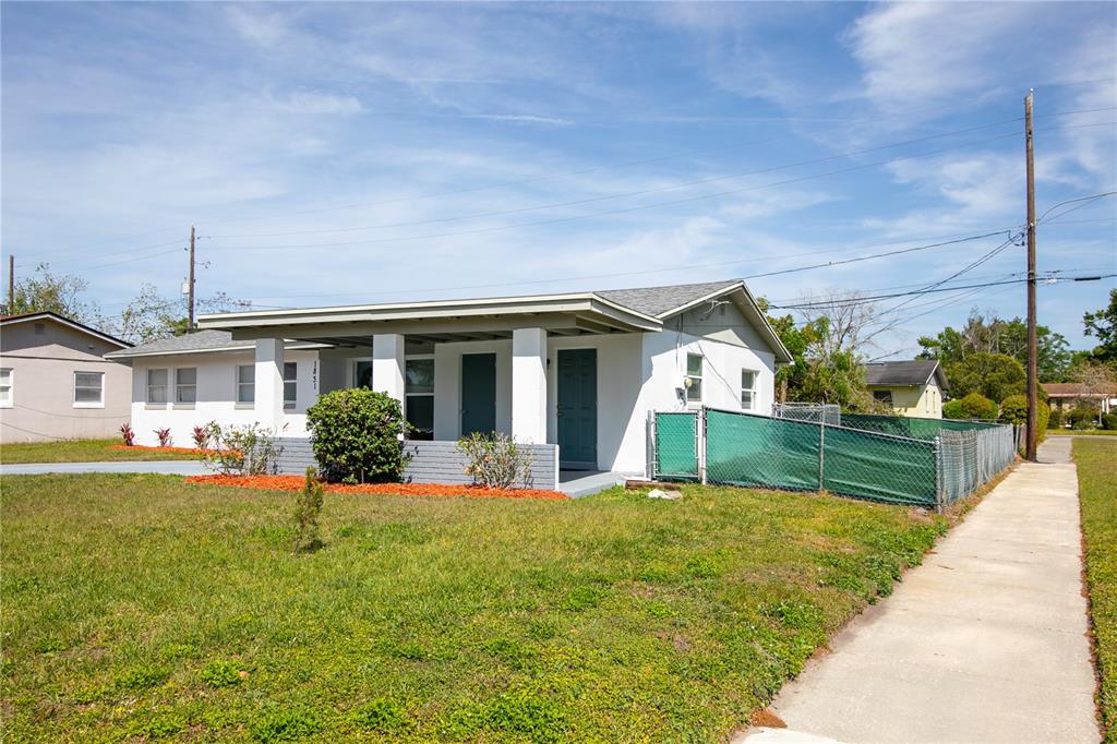 A white single-story house features a covered front porch and a green chain-link fence — 1831 AARON AVENUE, ORLANDO, FL