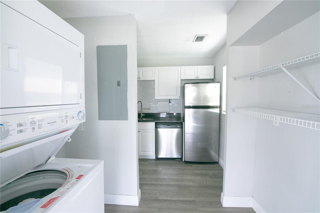A laundry area with a stacked washer-dryer leads into a kitchen with stainless steel appliances — 1831 AARON AVENUE, ORLANDO, FL