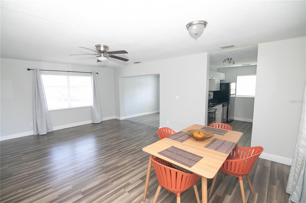 An open-concept living and dining area features wood-look flooring, light gray walls, and a ceiling fan — 1831 AARON AVENUE, ORLANDO, FL