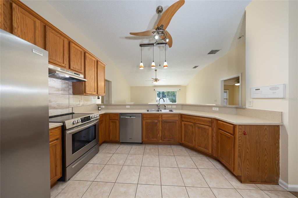 A kitchen features oak cabinets, stainless steel appliances, a tile floor, and a breakfast bar — 22 EMERSON DRIVE, PALM COAST, FL