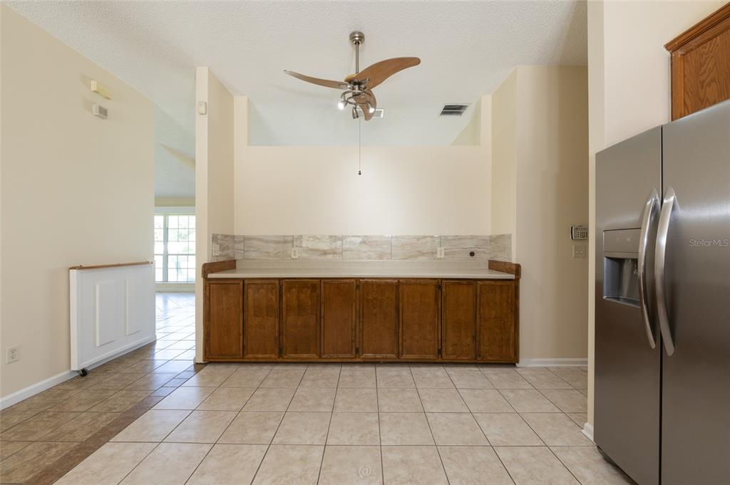 A kitchen area features wood cabinets, a light-colored countertop, tile flooring, and a ceiling fan — 22 EMERSON DRIVE, PALM COAST, FL