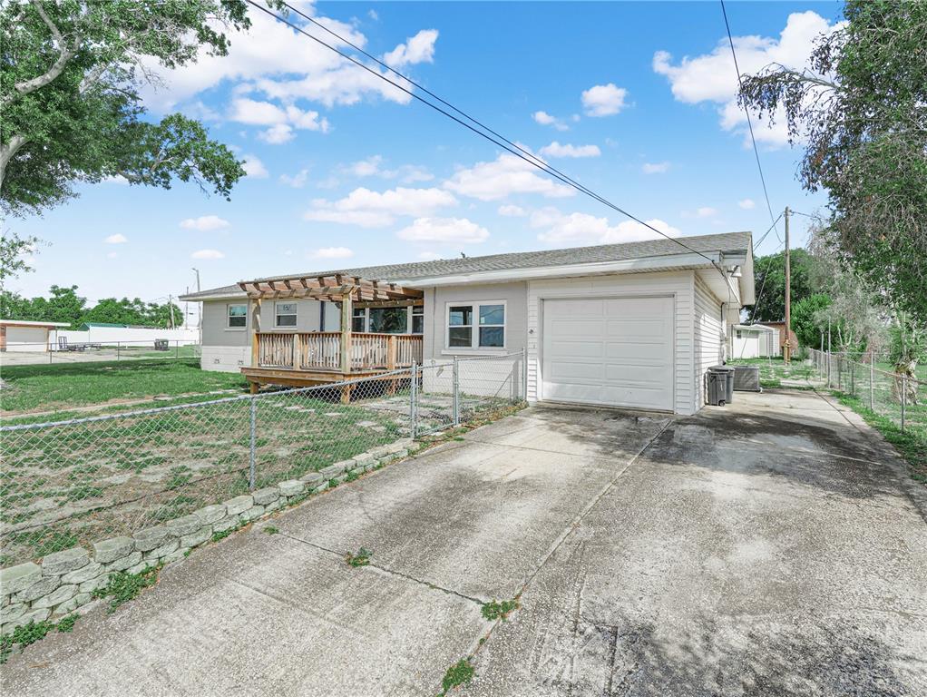 A single-story house with a wooden deck, pergola, and attached garage sits on a lawn — 231 RIDGE MANOR DRIVE, LAKE WALES, FL