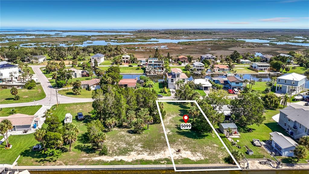 An aerial view shows a vacant waterfront lot outlined in white near a canal — 5111 CEDARBROOK LANE, HERNANDO BEACH, FL