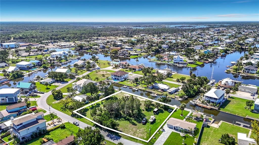An aerial view shows a vacant, rectangular lot surrounded by residential houses and canals — 5111 CEDARBROOK LANE, HERNANDO BEACH, FL