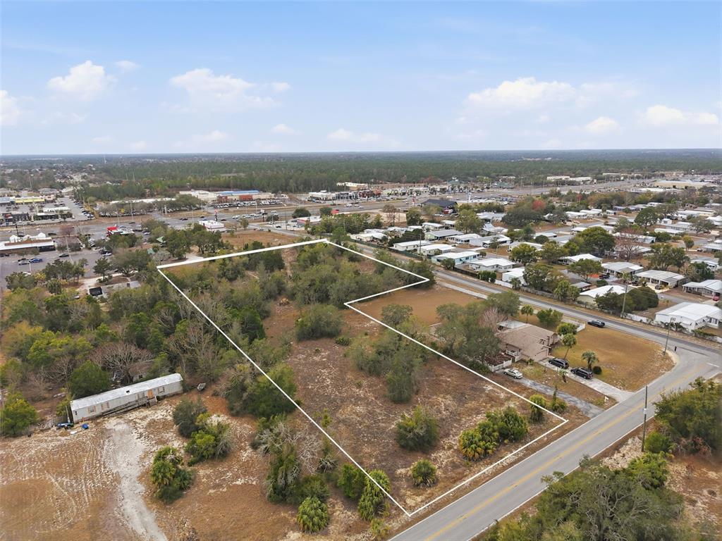 An aerial view shows a vacant, L-shaped lot bordered by a road and residential properties — 0 WEEPING WILLOW ROAD, BROOKSVILLE, FL