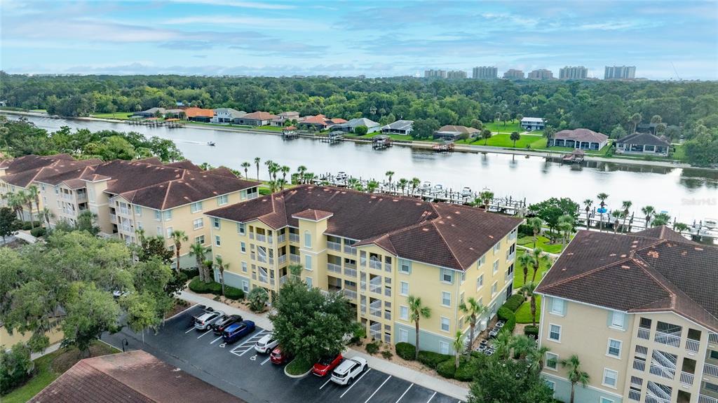 An aerial view shows multi-story apartment buildings with brown roofs situated along a waterfront canal — 700 CANOPY WALK LANE UNIT 732, PALM COAST, FL