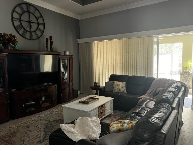 A living room features a large dark wood entertainment center, a sectional sofa, and a clock — 845 10TH AVENUE NE, NAPLES, FL
