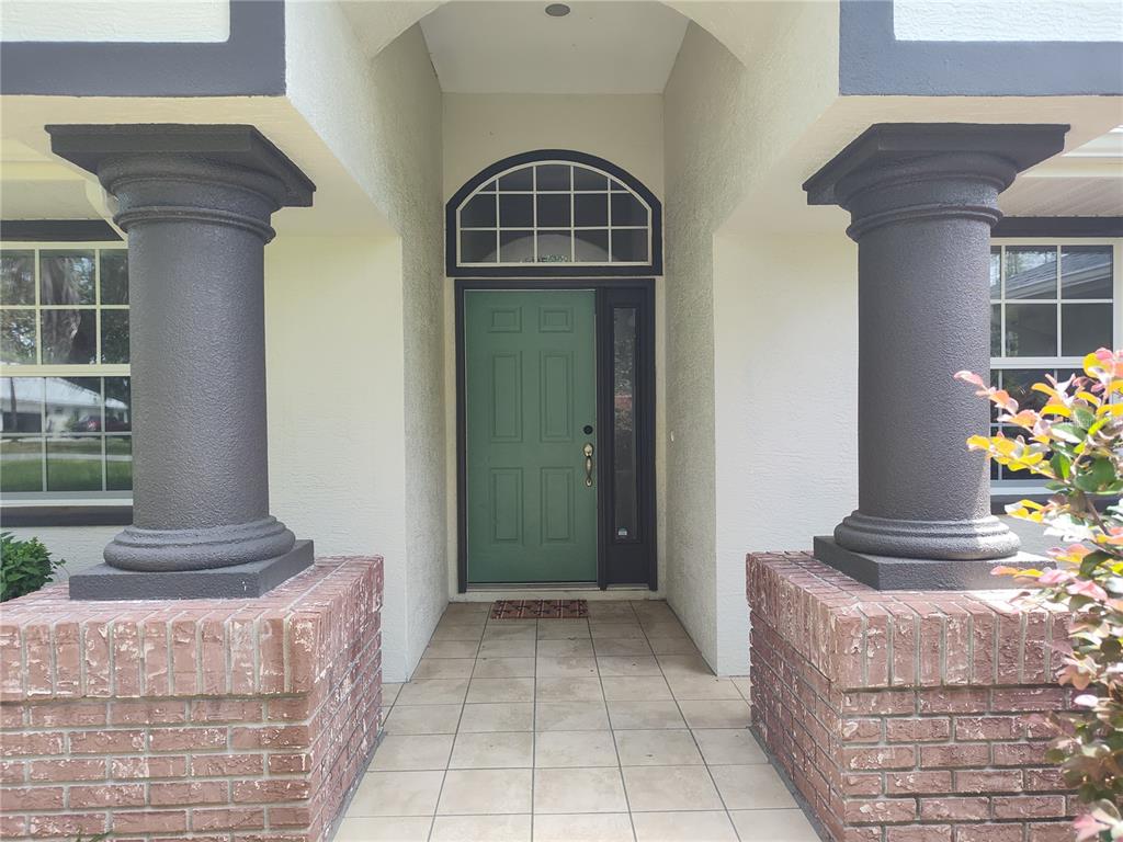 A front entryway features a green door, arched transom window, and two dark columns on brick — 2905 W BEAMWOOD DRIVE, BEVERLY HILLS, FL