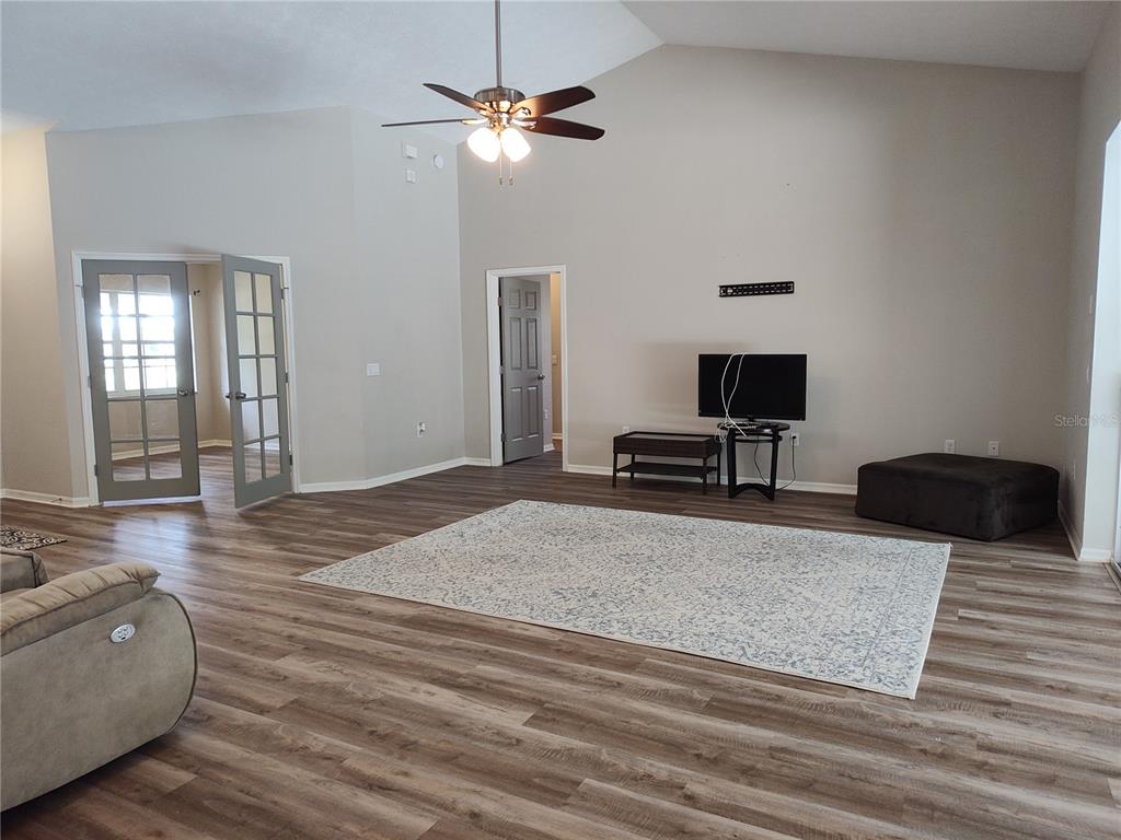 A living room features vaulted ceilings, wood-look flooring, a ceiling fan, and French doors — 2905 W BEAMWOOD DRIVE, BEVERLY HILLS, FL