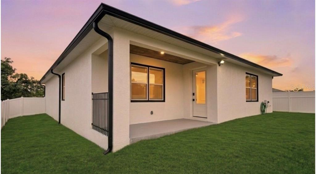 The exterior of a house features a covered patio, white stucco walls, and black trim — 105 NORTH BOULEVARD E, DAVENPORT, FL