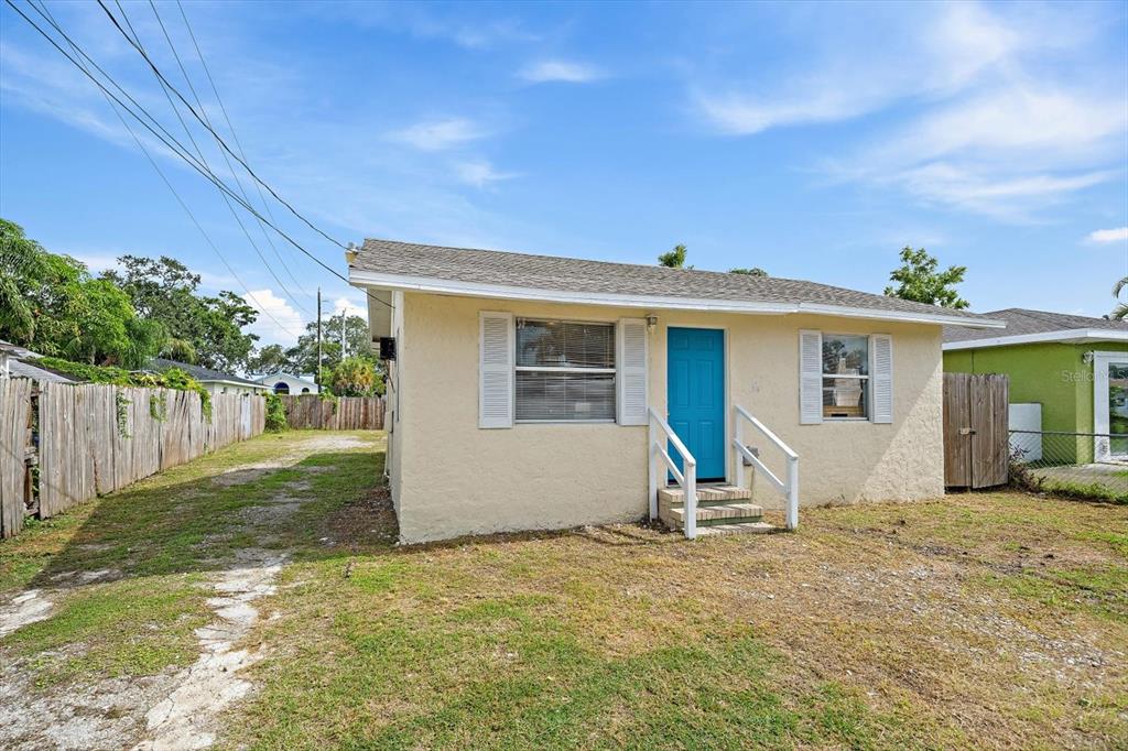 A single-story house with beige stucco siding, a bright blue door, and a gravel driveway — 516 29TH STREET E, PALMETTO, FL