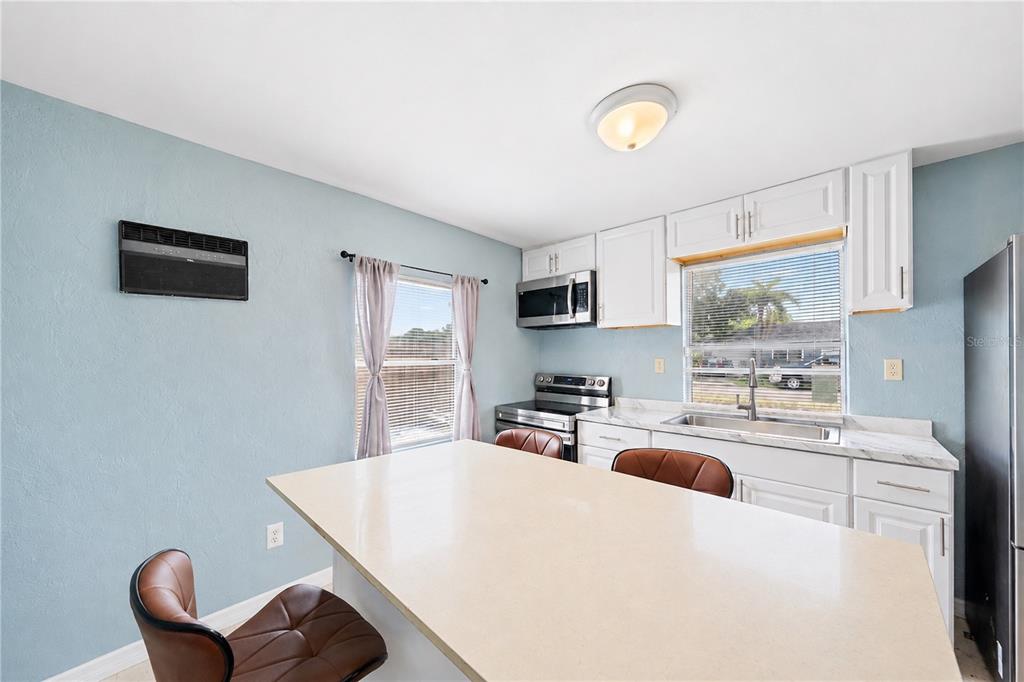 A kitchen features white cabinets, a large island, stainless steel appliances, and light blue walls — 516 29TH STREET E, PALMETTO, FL