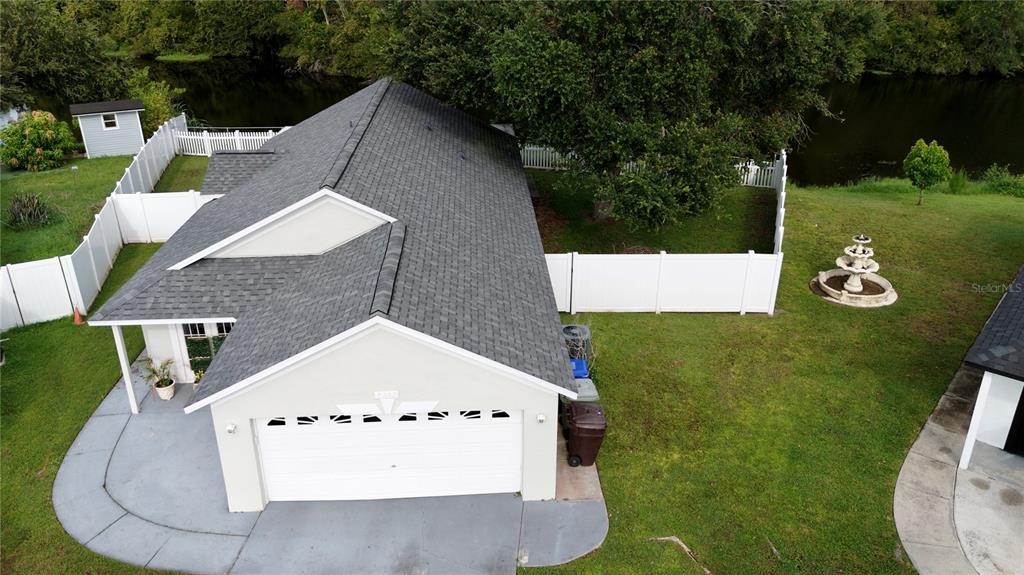 An aerial view shows a house with a gray shingled roof, garage, and fenced backyard — 2412 SONJA COURT, KISSIMMEE, FL