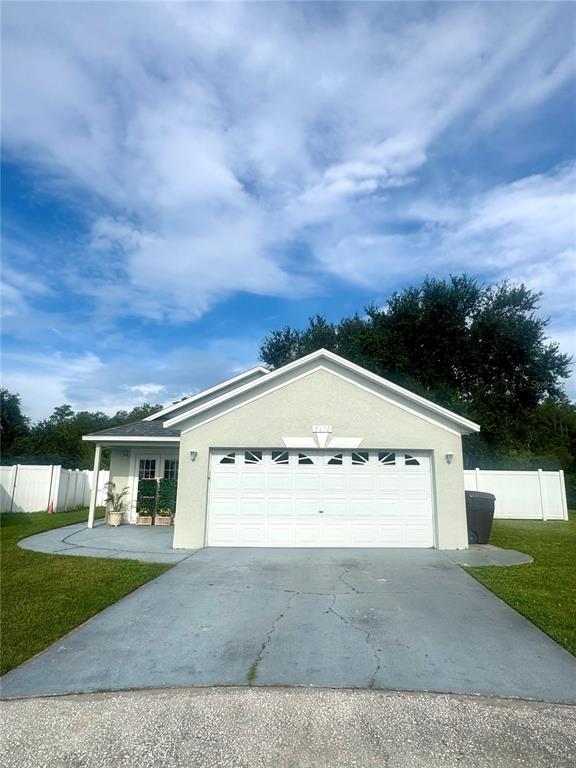 A single-story house with a white garage door, a concrete driveway, and a white fence — 2412 SONJA COURT, KISSIMMEE, FL