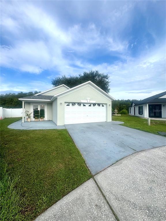 A light-colored single-story house with a two-car garage and a concrete driveway — 2412 SONJA COURT, KISSIMMEE, FL