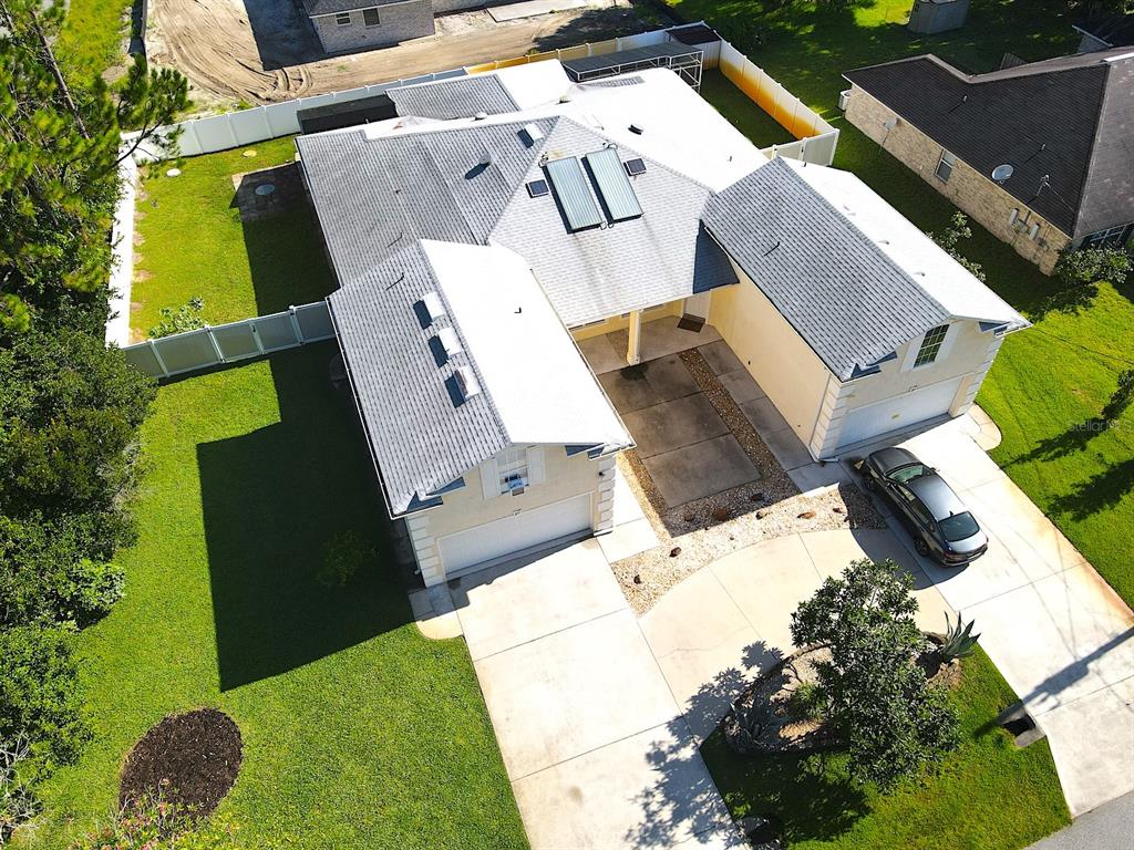 An aerial view shows a single-story house with a gray roof, solar panels, and driveway — 20 REGIS LANE UNIT A, PALM COAST, FL