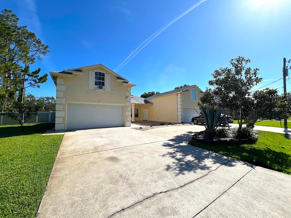 A two-story yellow house with a two-car garage and a concrete driveway — 20 REGIS LANE UNIT A, PALM COAST, FL